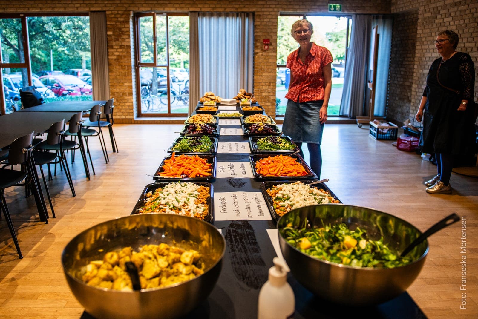 A long table of bowls and trays with salads and hot dishes, ready for dinner