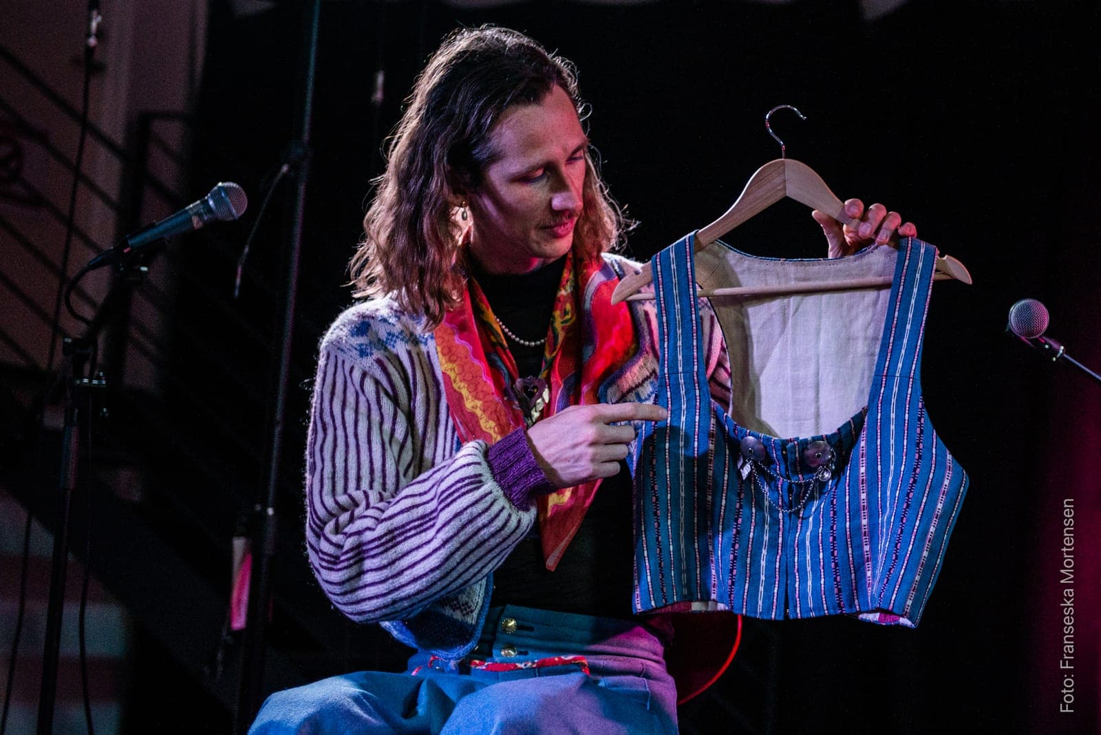 Fredy Clue holding up a striped waistcoat on a hanger during the talk about Bäckadräkten