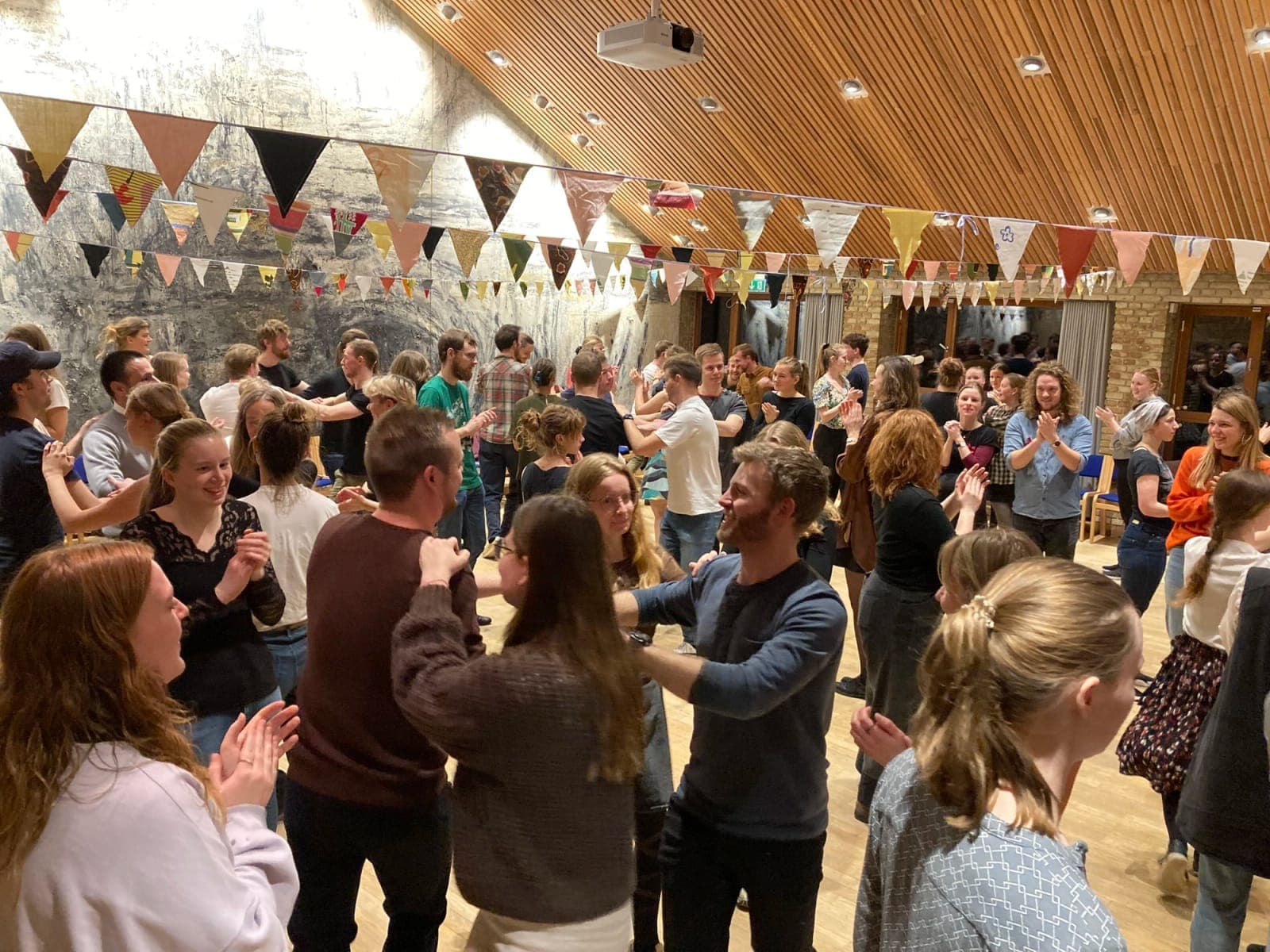 Deltagere hos Nordisk Dans Aarhus danser parvis og klapper under farverige vimpler