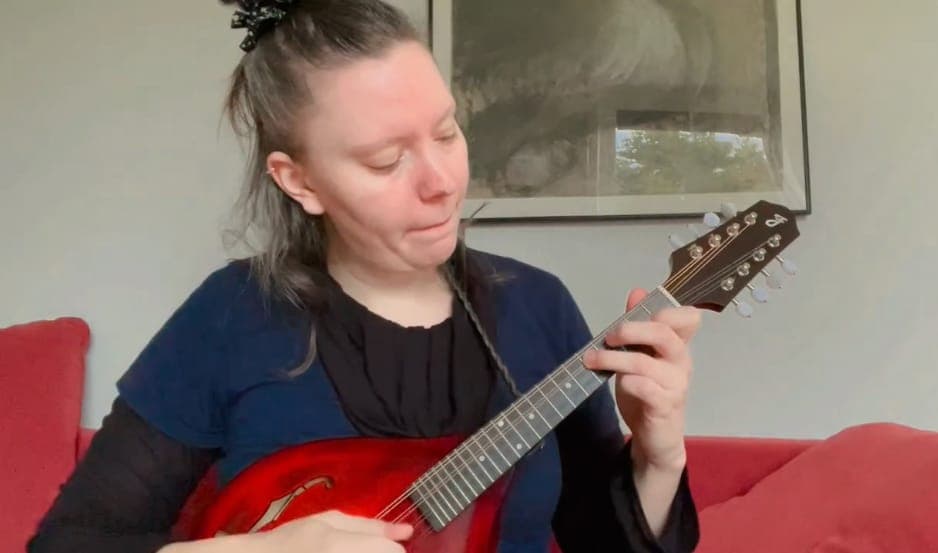 Bodil Frimodt Rønnow spiller mandolin i en rød sofa