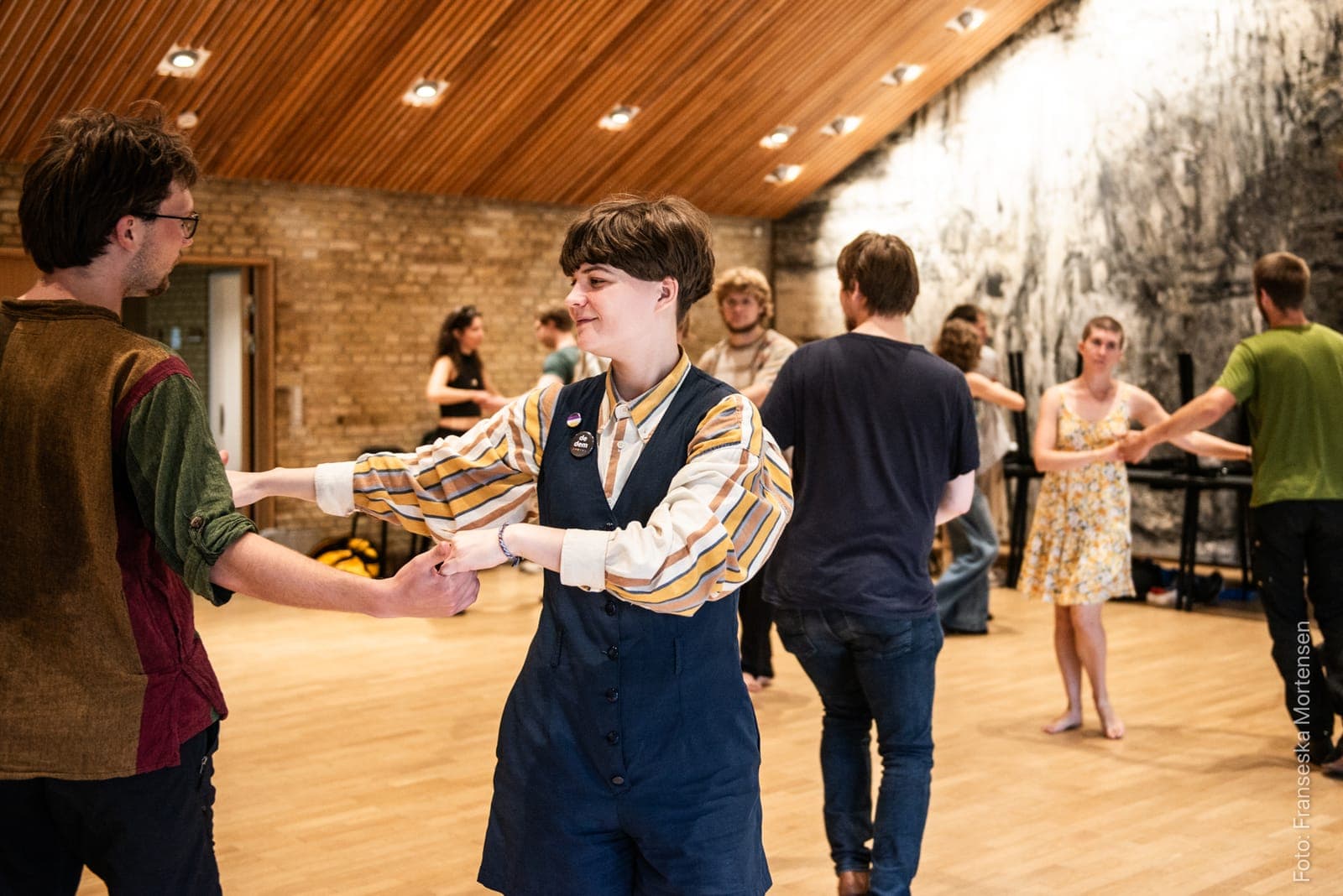 To dansere holder hinanden i hænderne og øver en tur, mens flere par danser bag dem
