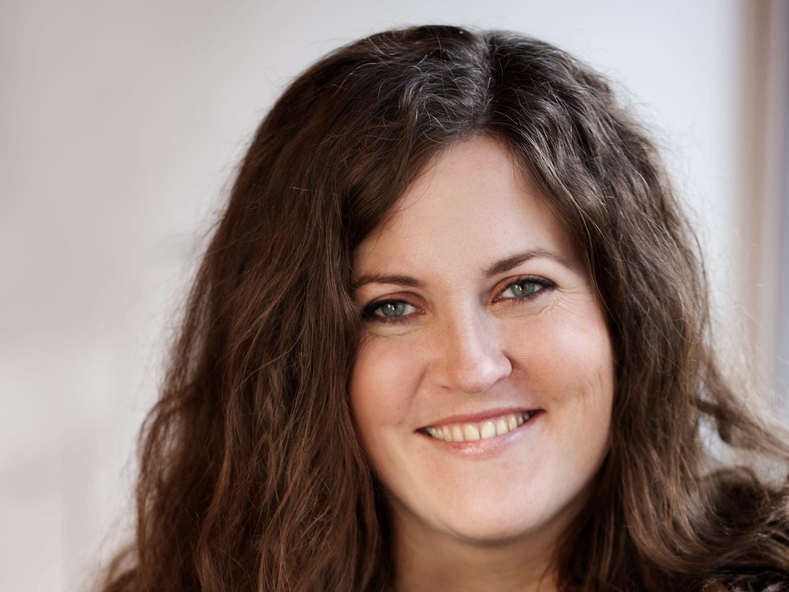 Portræt af Mette Kathrine Stærk med langt mørkt hår og et smil